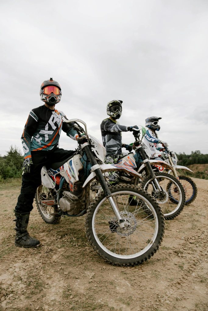 Three dirt bike riders in protective gear ready for motocross adventure outdoors.